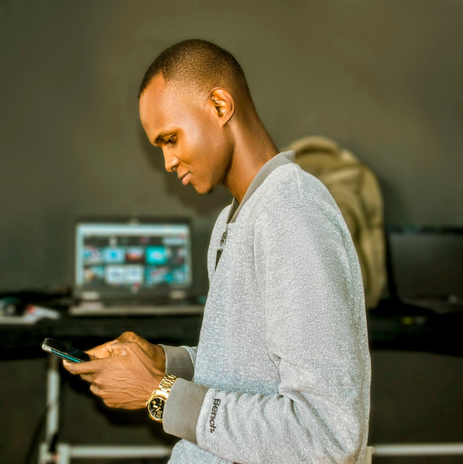 A person making a payment on a mobile phone beside a laptop
