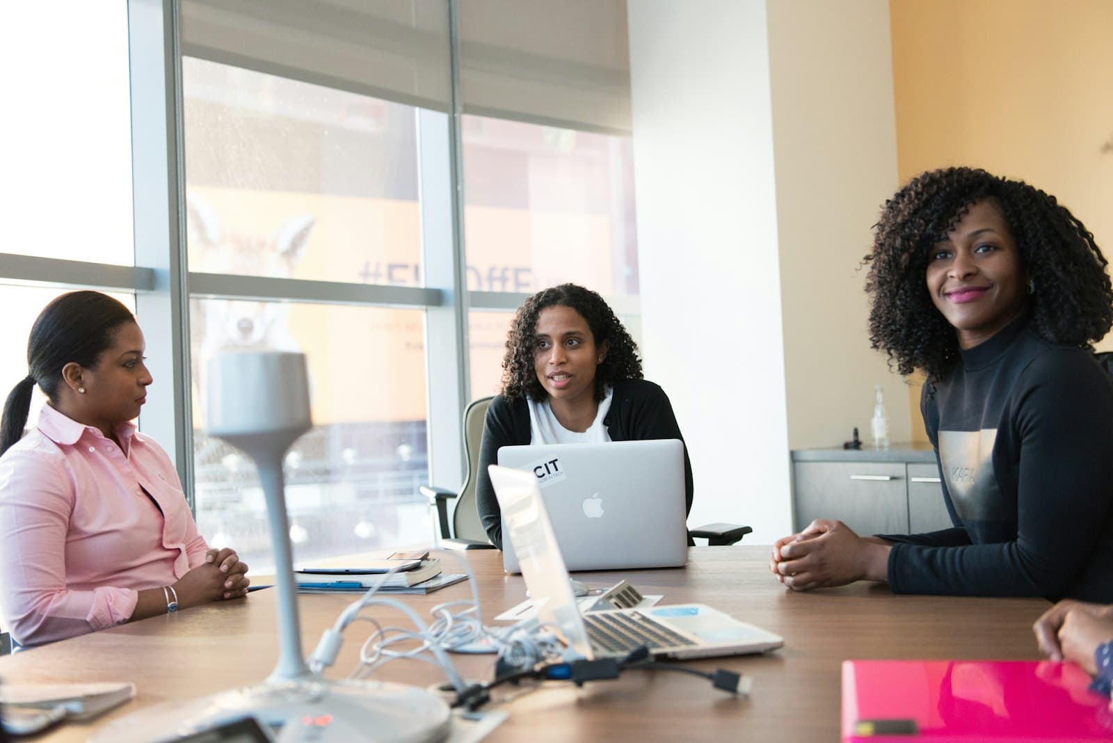 Colleagues collaborating around a laptop in a meeting room